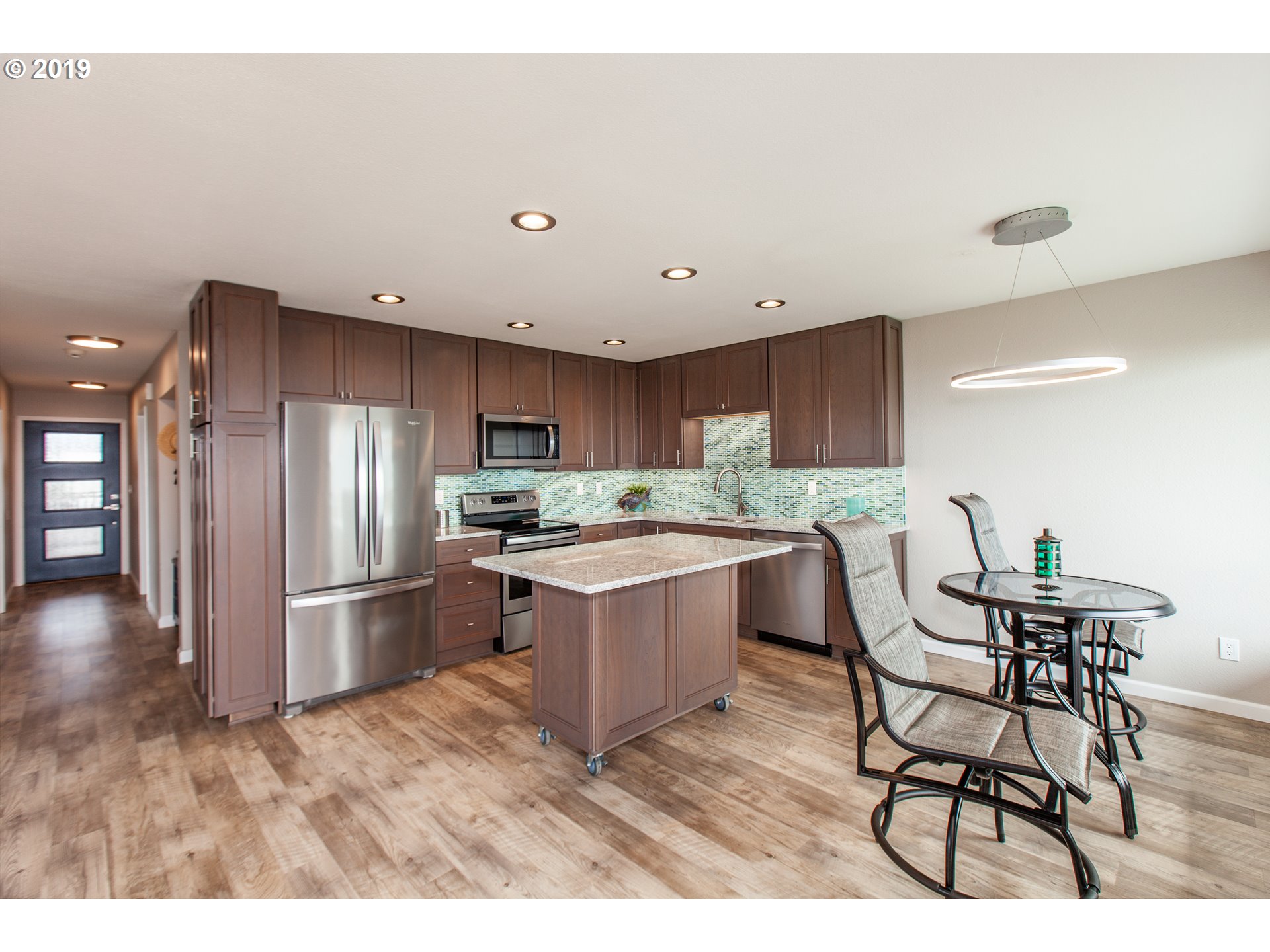 Windward Condo Gearhart, OR 97138 - Photo 13 of 24 a kitchen with stainless steel appliances kitchen island granite countertop a table chairs and a refrigerator