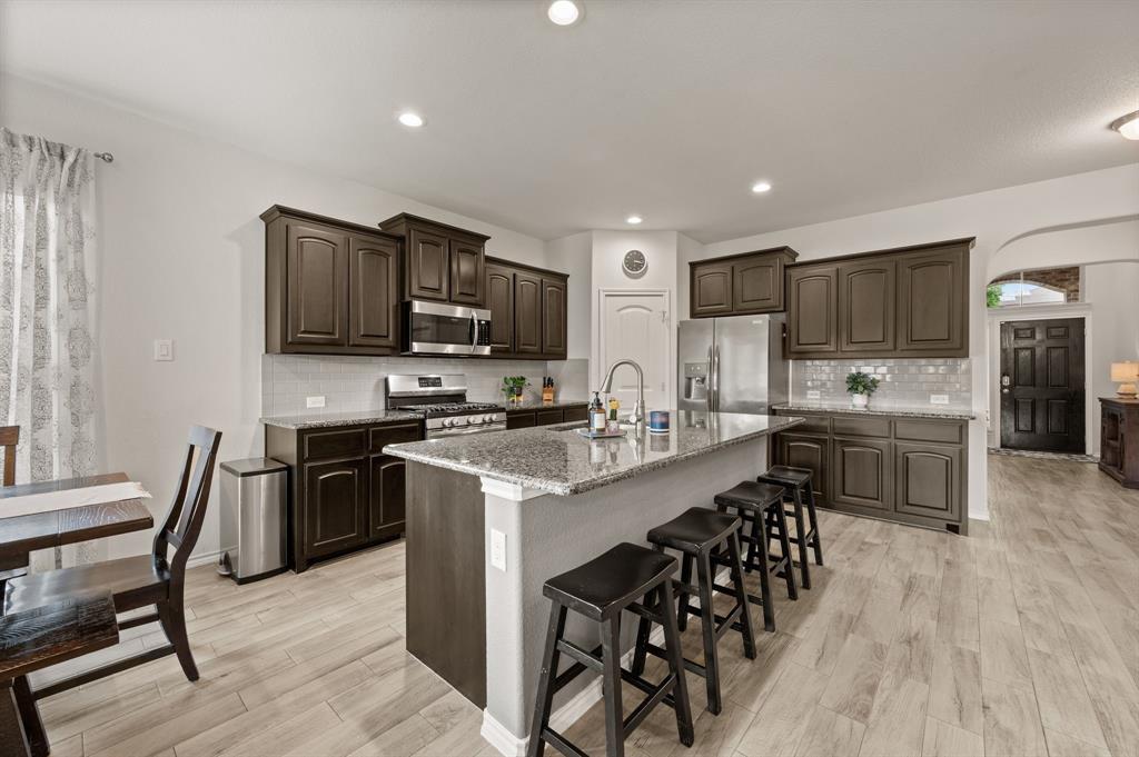 15817 White Mill Road Fort Worth, TX 76177 - Photo 11 of 27 a open kitchen with stainless steel appliances granite countertop a stove top oven a sink dishwasher a dining table and chairs with wooden floor