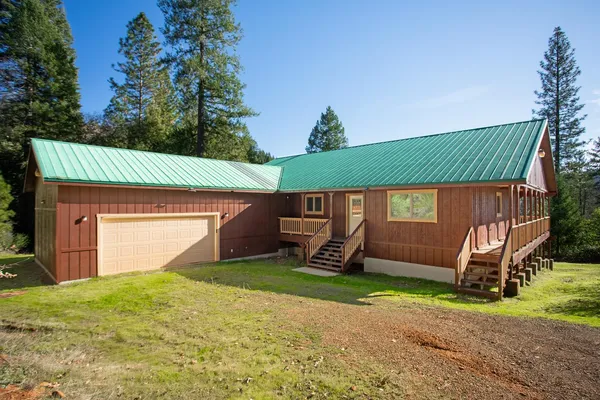 a backyard of a house with wooden fence and large trees