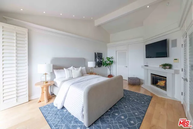 a bed room with a bed a flat screen tv and a fireplace