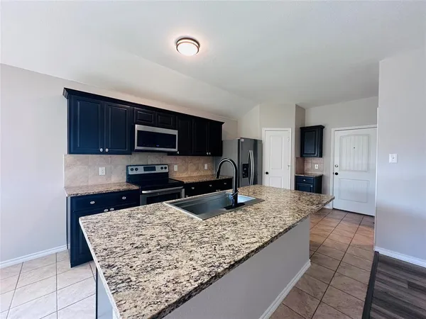 a kitchen with granite countertop wooden cabinets and stainless steel appliances