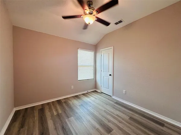 a view of an empty room with window and chandelier fan
