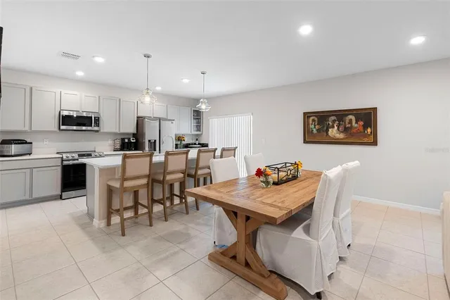 a kitchen with stainless steel appliances kitchen island granite countertop a table chairs and a refrigerator