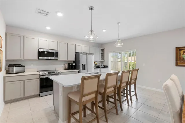 a kitchen with stainless steel appliances granite countertop a refrigerator a stove a sink a dining table and chairs with wooden floor