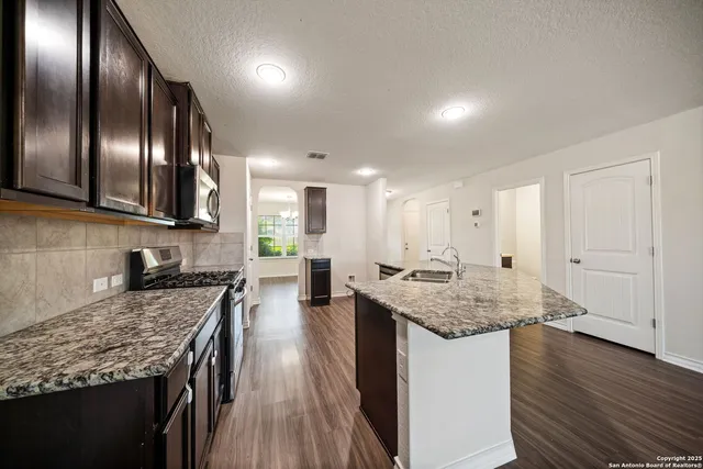 a kitchen with stainless steel appliances granite countertop lots of counter top space and wooden floor