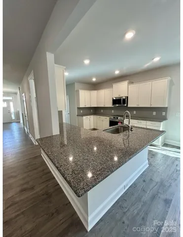 a large kitchen with stainless steel appliances granite countertop a large counter top and a stove top oven