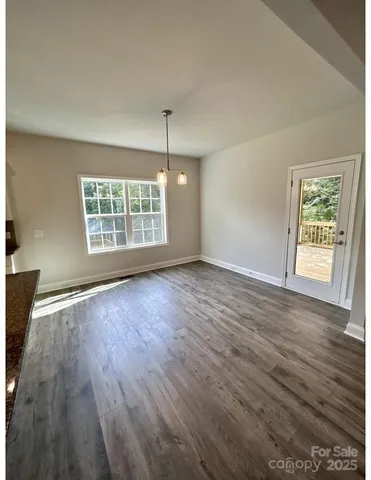 an empty room with wooden floor cabinet and windows