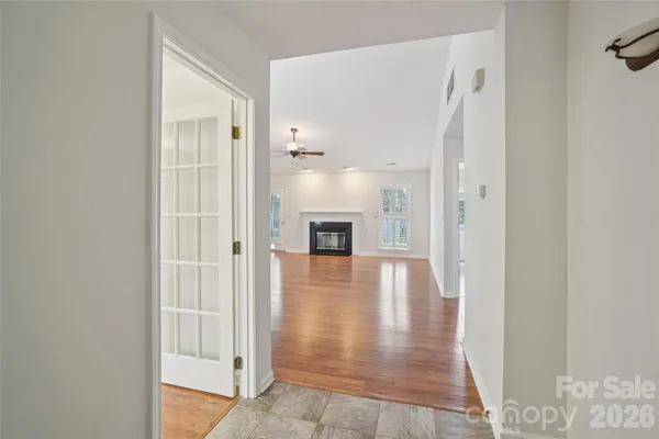 a view of a hallway with wooden floor and a bathroom