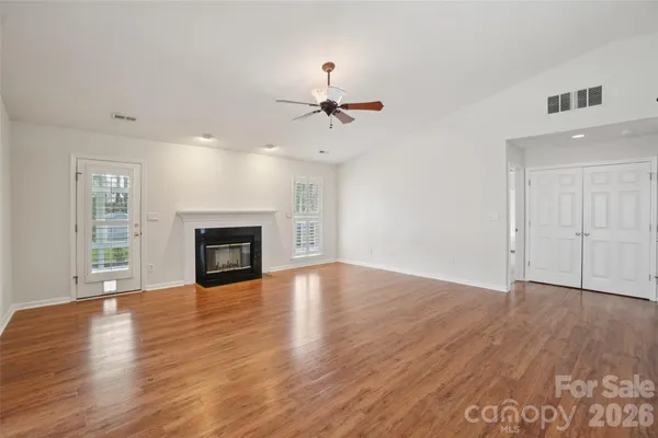 an empty room with wooden floor fireplace and windows