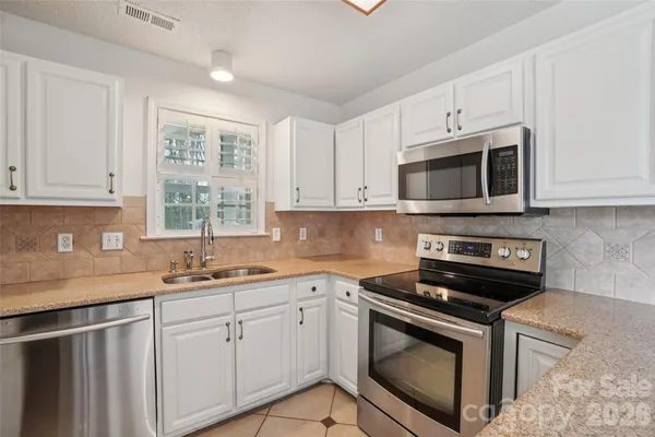 a kitchen with cabinets stainless steel appliances a sink and a window