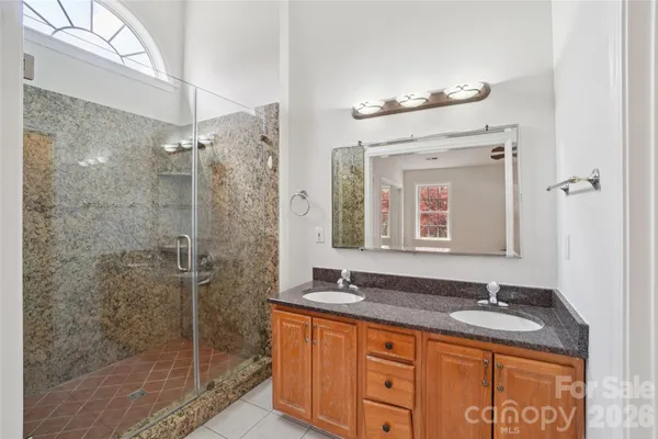a bathroom with a granite countertop sink a mirror and shower