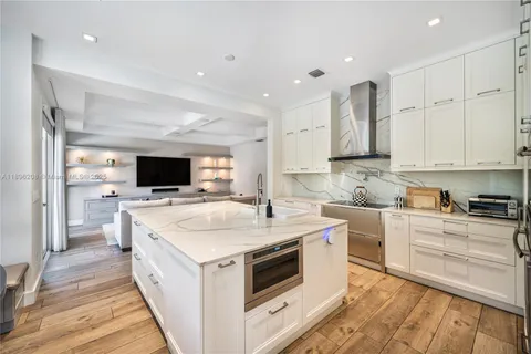 a large kitchen with stainless steel appliances kitchen island granite countertop a sink and a stove top oven with wooden floor