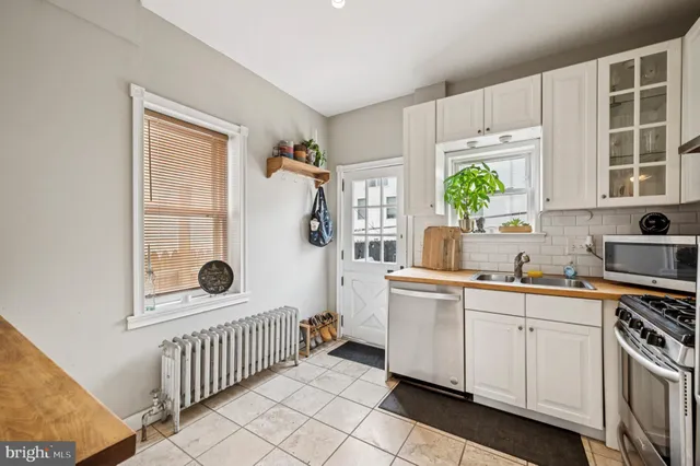 a kitchen with white cabinets and window