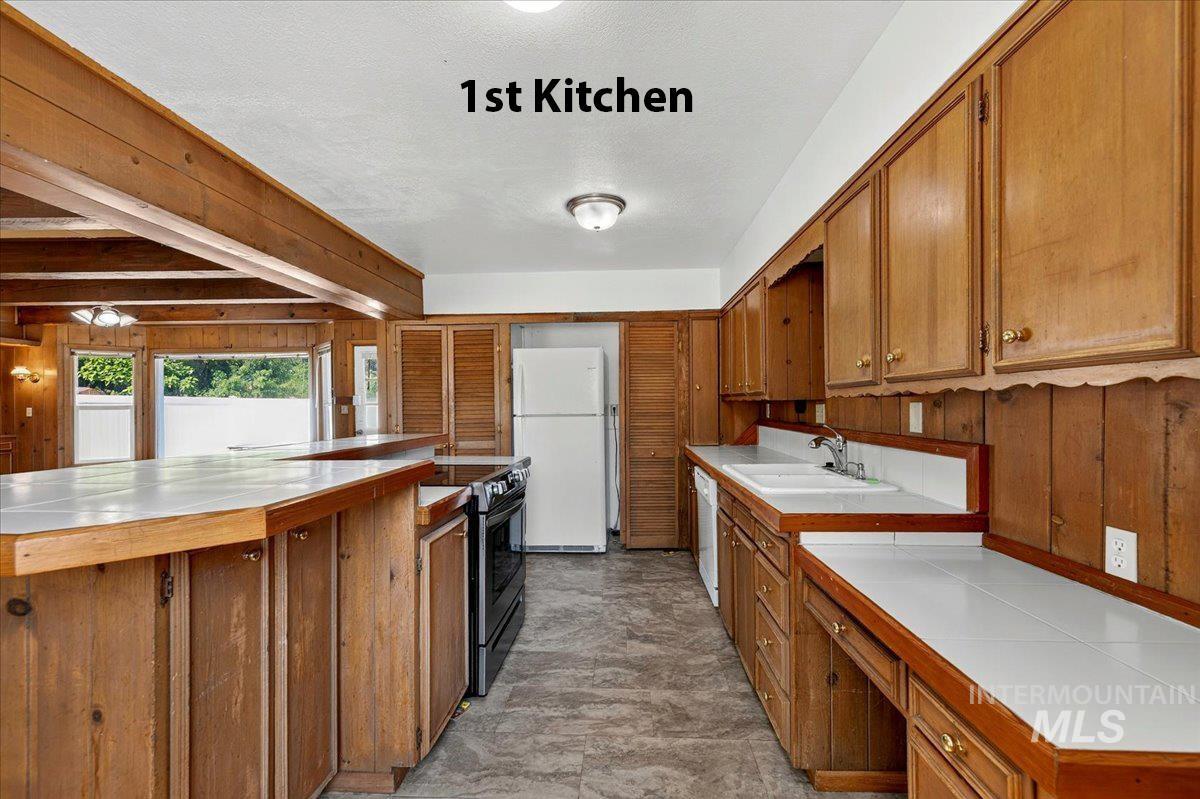 2160 South Five Mile Road Boise, ID 83709 - Photo 7 of 41 Kitchen featuring abundant wood cabinetry, tile countertops, dual-basin sink, and a black range