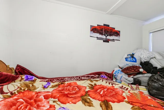 a bedroom with a bed a mirror and a flat tv screen on dresser
