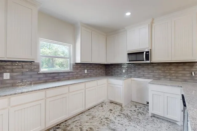 a kitchen with white cabinets sink and window