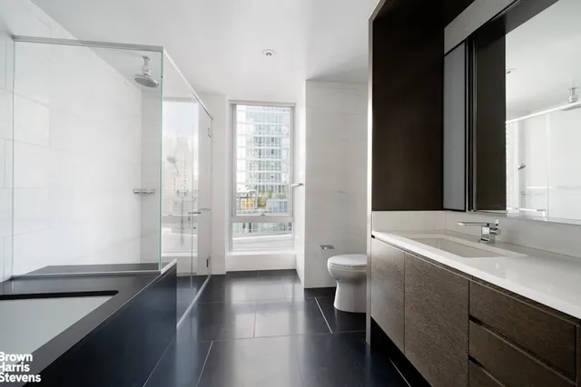 a spacious bathroom with a double vanity sink a toilet and a shower
