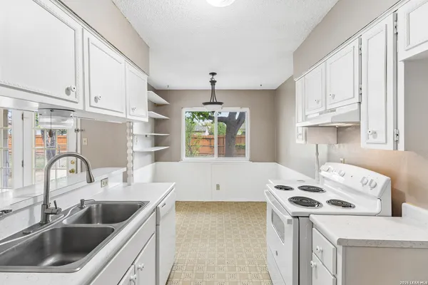 a kitchen with stainless steel appliances granite countertop a sink stove and white cabinets with wooden floor