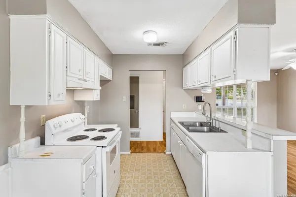 a kitchen that has a lot of white cabinets and stainless steel appliances