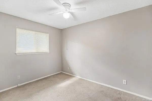 an empty room with a window and ceiling fan