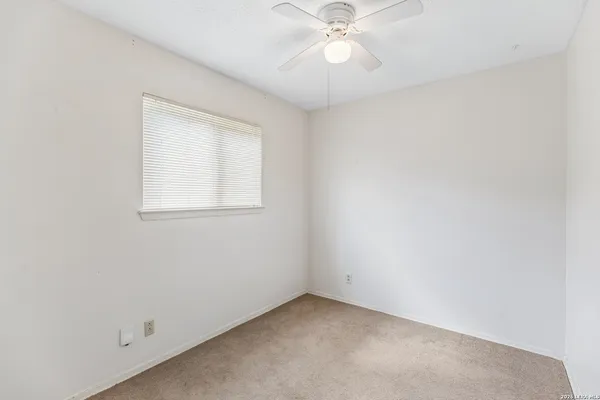 an empty room with a window and a fan