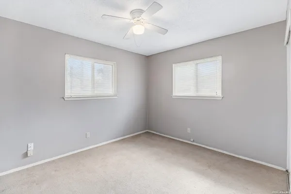 an empty room with a window and a fan