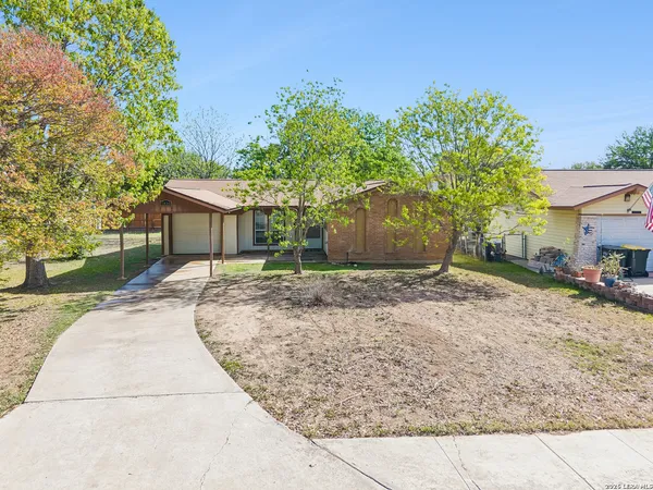 a backyard of a house with large trees and outdoor seating