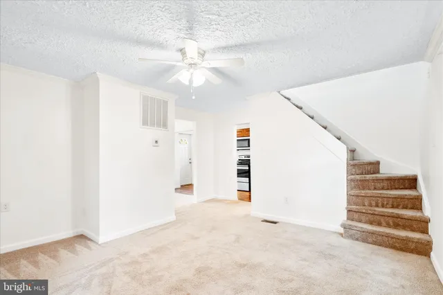 an empty room with windows and fan