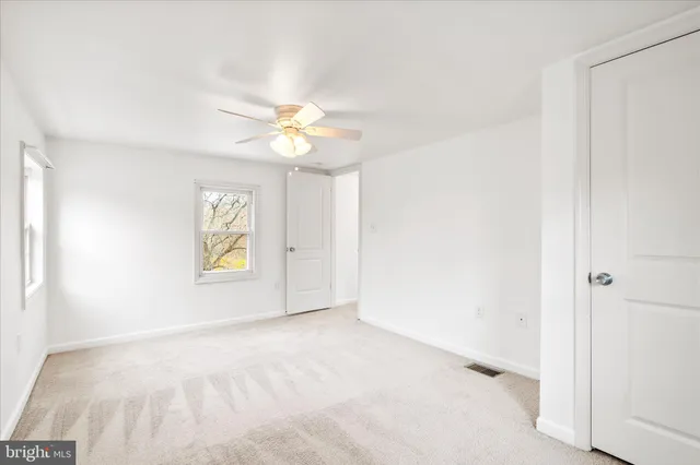 an empty room with windows and fan