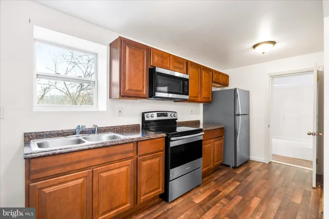 a kitchen with stainless steel appliances granite countertop a sink a stove and a refrigerator