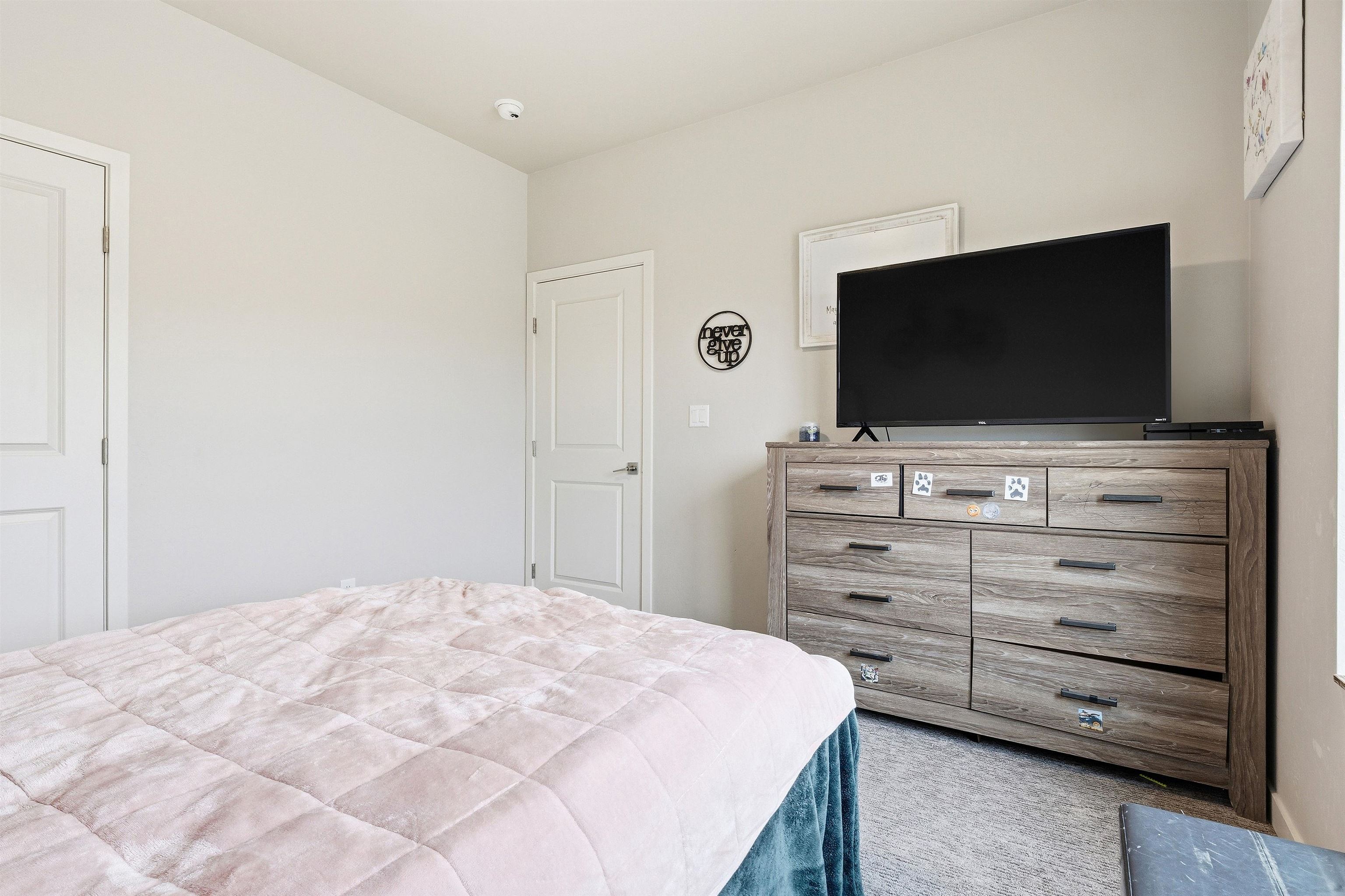 623 Thunder Ridge Drive Grand Junction, CO 81504 - Photo 13 of 40 a bedroom with a bed and a flat screen tv in white walls