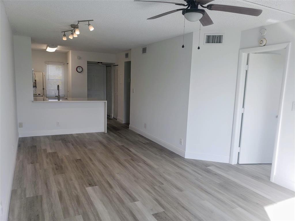 a view of a room with wooden floor and a ceiling fan