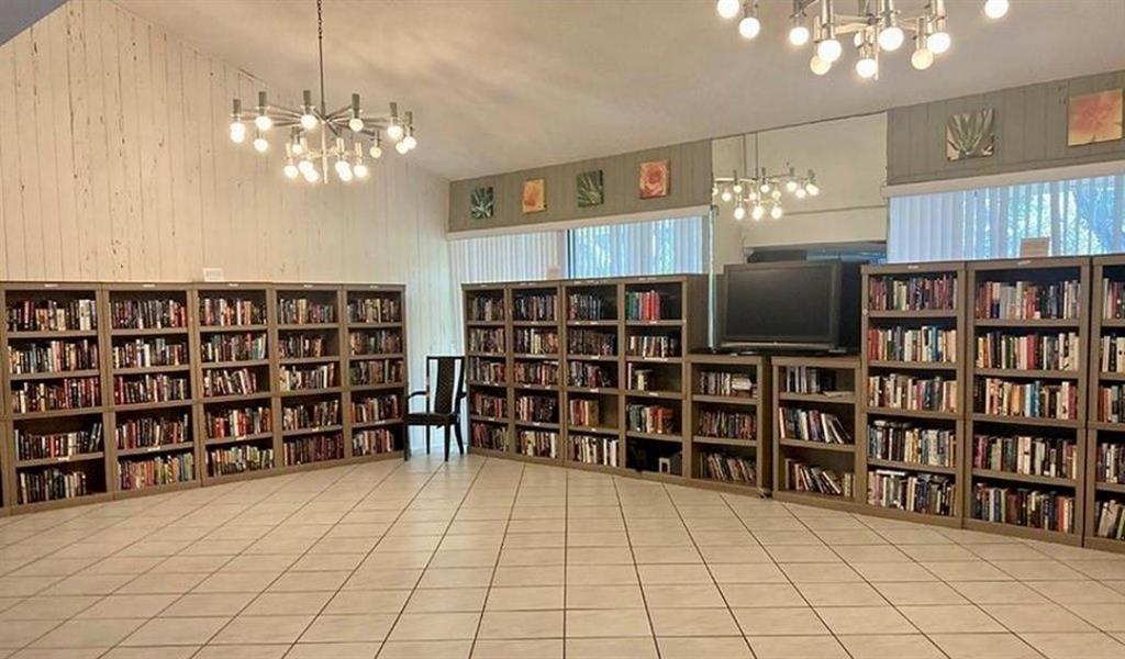 2216 North Cypress Bend Drive, Unit 504 Pompano Beach, FL 33069 - Photo 32 of 33 a living room with a bookshelf and a chandelier