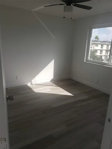 an empty room with wooden floor cabinet and windows