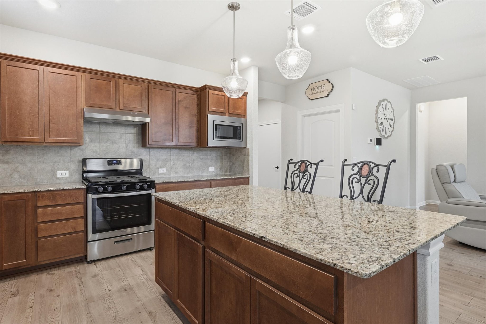 113 Lafayette Street Georgetown, TX 78633 - Photo 11 of 39 Kitchen featuring a large island with a stone-finish countertop, wood-finish cabinetry, stainless steel appliances, and wood-finish flooring