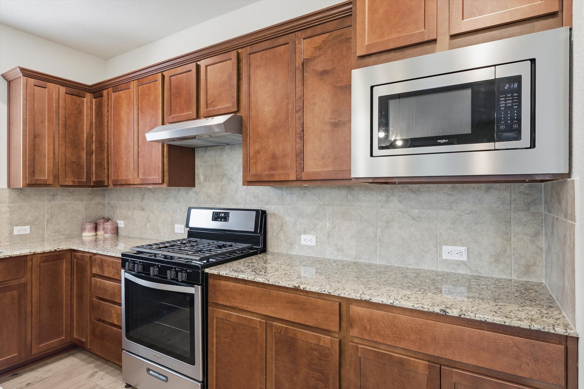 113 Lafayette Street Georgetown, TX 78633 - Photo 13 of 39 Kitchen with rich wood cabinetry, granite-style countertops, stainless steel appliances, and a tiled backsplash