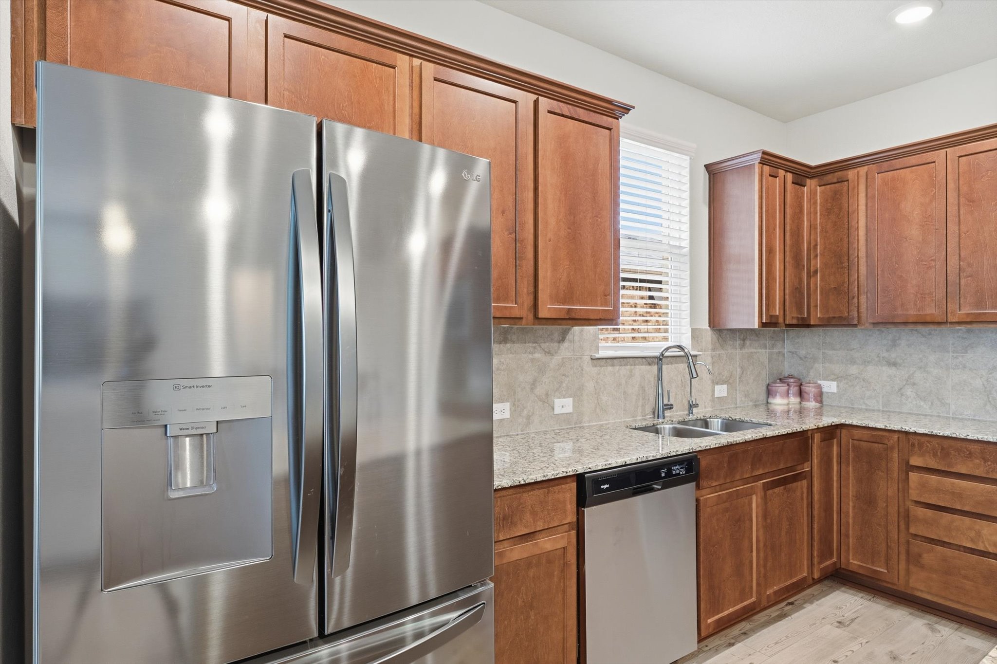113 Lafayette Street Georgetown, TX 78633 - Photo 14 of 39 Kitchen featuring stainless steel French door refrigerator with ice and water dispenser, warm-toned cabinetry, granite countertops, and stone tile backsplash