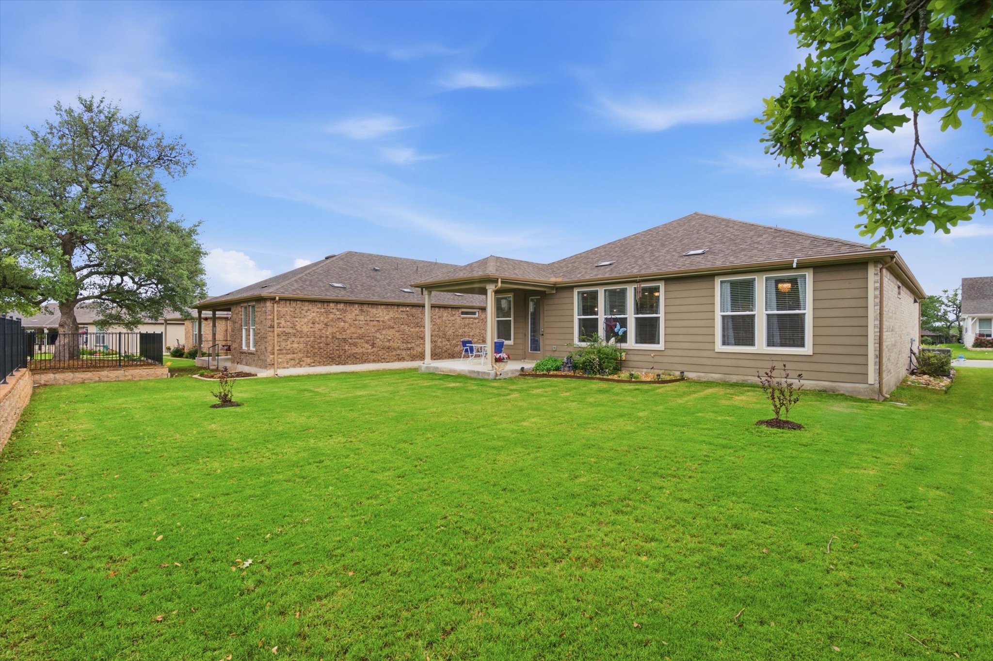 113 Lafayette Street Georgetown, TX 78633 - Photo 35 of 39 Expansive green lawn with a covered patio, tan siding, brick exterior, and a large mature tree