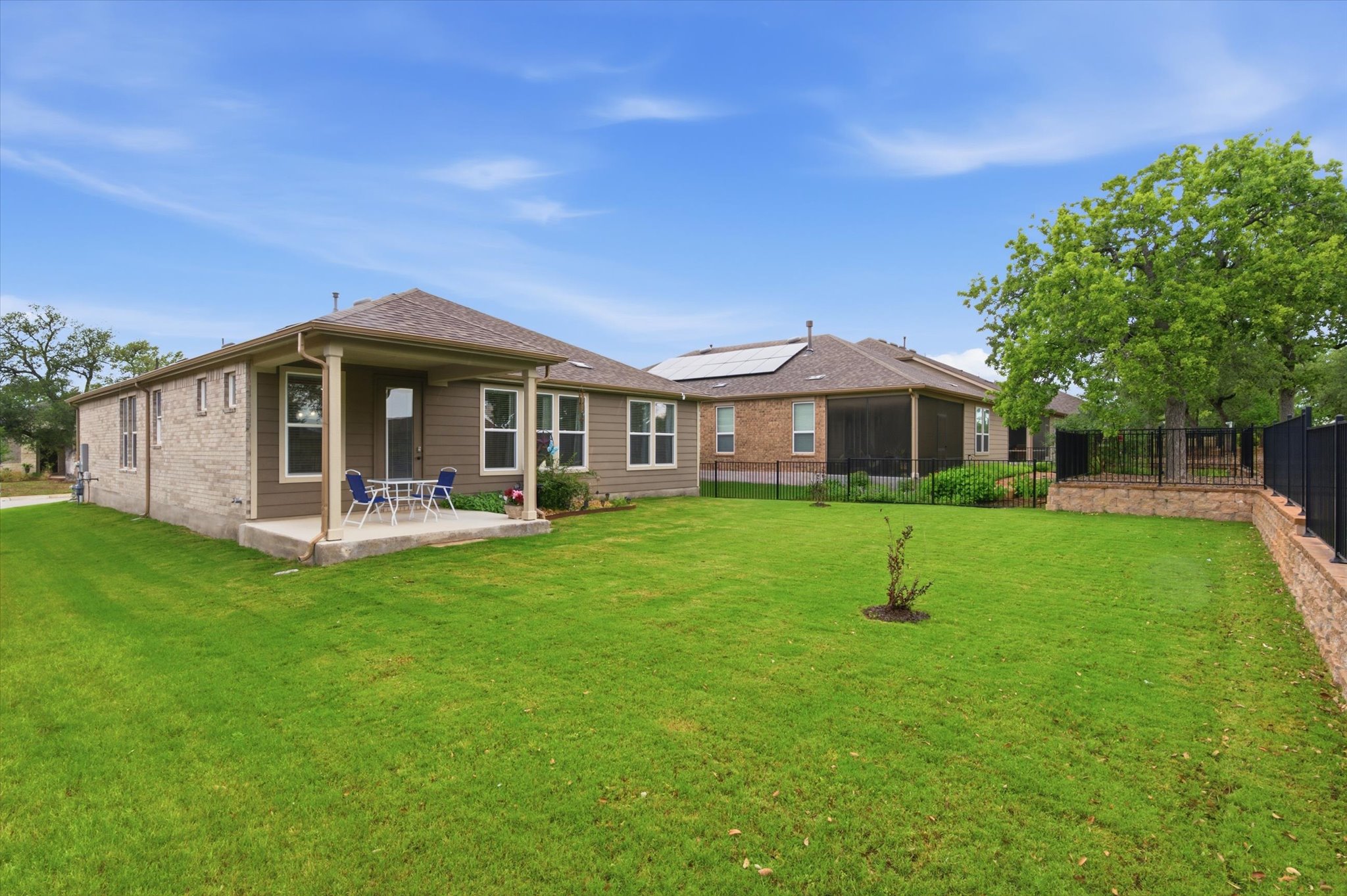 113 Lafayette Street Georgetown, TX 78633 - Photo 36 of 39 Expansive backyard featuring a covered patio, extensive green lawn, and a stone retaining wall with a black metal fence