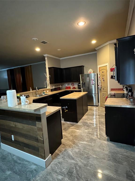 104 Anthony Lane Red Oak, TX 75154 - Photo 4 of 16 Kitchen featuring dark cabinets, crown molding, light countertops, freestanding refrigerator, and a peninsula