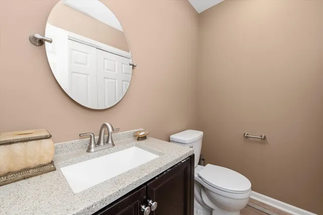 a bathroom with a granite countertop toilet sink and mirror