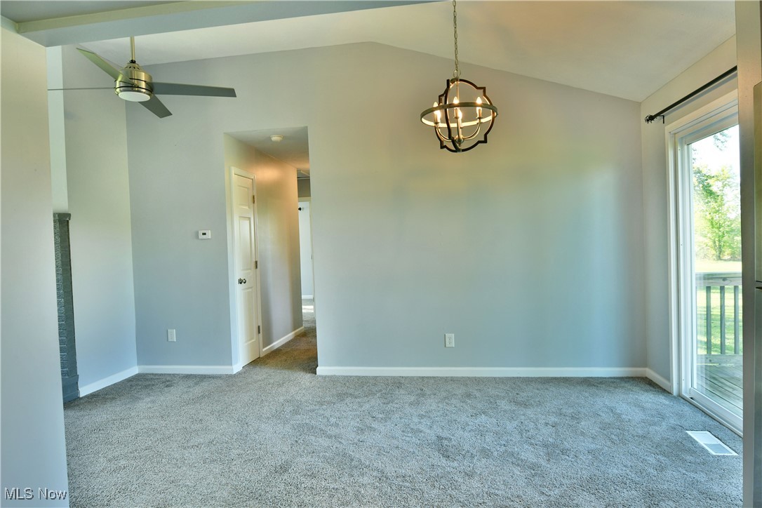 4461 Ridge Road Cortland, OH 44410 - Photo 16 of 47 Spare room featuring ceiling fan with notable chandelier, vaulted ceiling, and light carpet