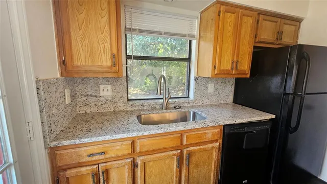 a bathroom with a granite countertop sink and a refrigerator