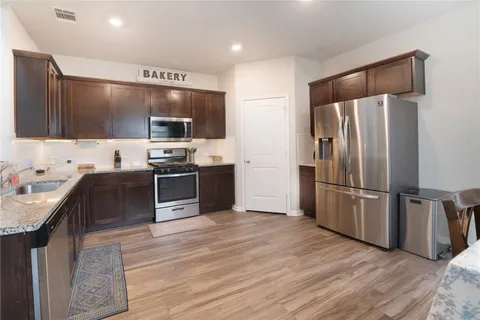 a kitchen with stainless steel appliances wooden floor sink and wooden cabinets