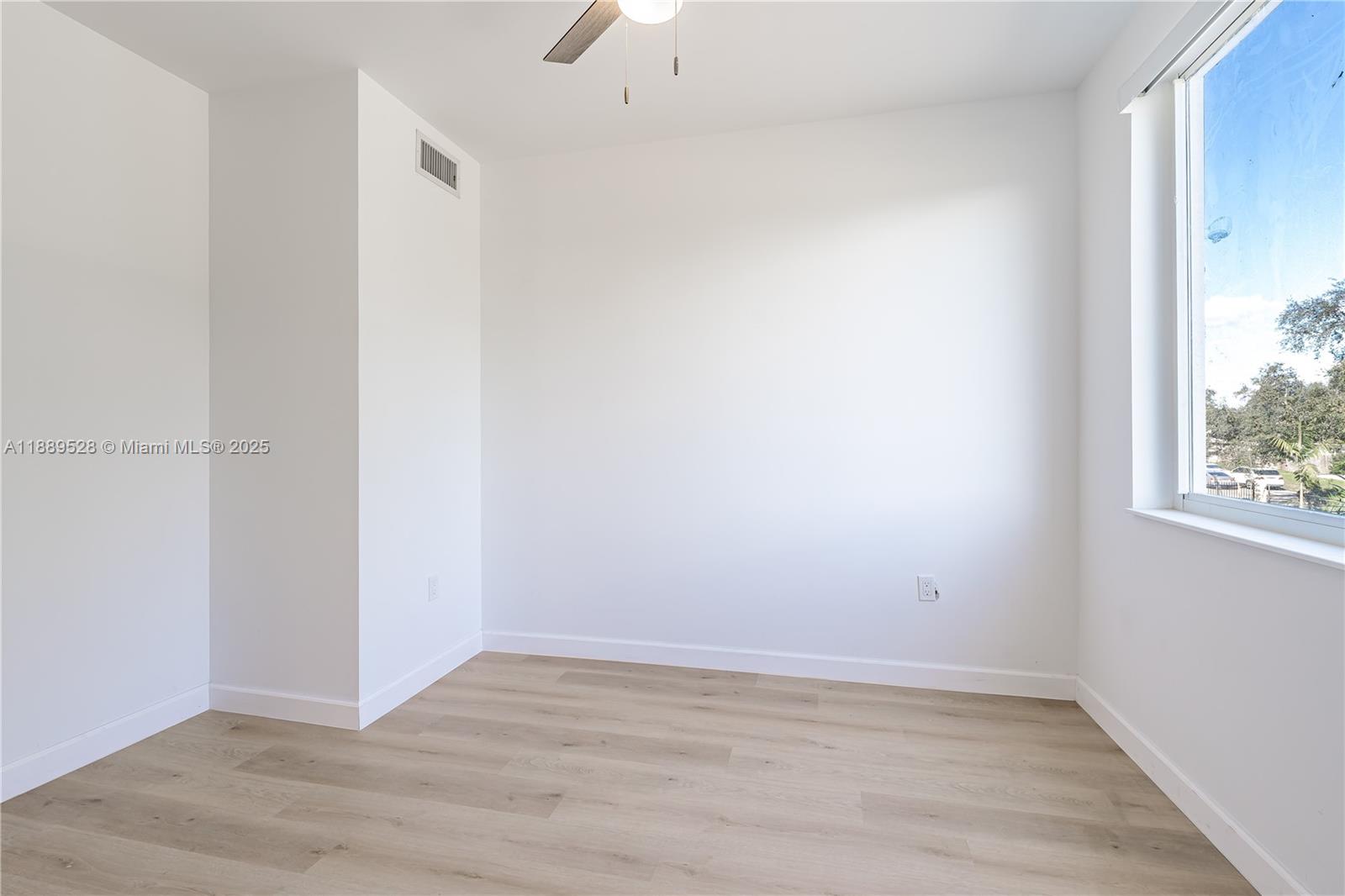 2575 Southwest 64th Avenue, Unit 7 Miramar, FL 33023 - Photo 7 of 13 a view of an empty room with wooden floor and a window