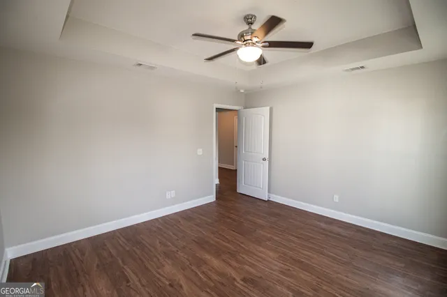 an empty room with wooden floor and ceiling fan