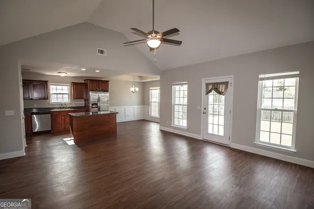 a view of a livingroom with furniture wooden floor and a kitchen