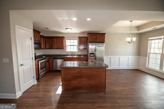 a large kitchen with stainless steel appliances granite countertop a stove and a wooden floors