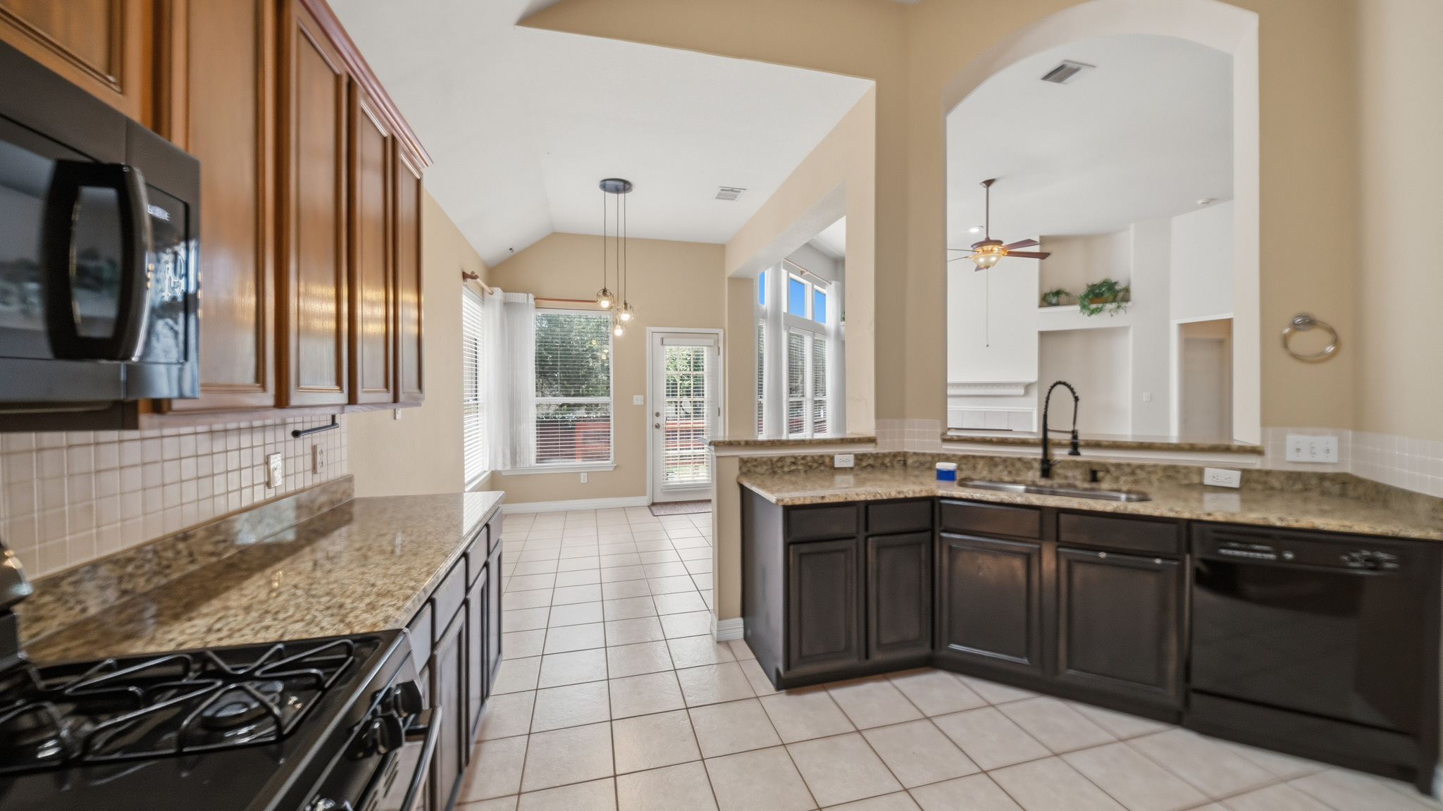 1108 Antelope Ridge Cedar Park, TX 78613 - Photo 6 of 27 A well-lit kitchen with granite counters and rich wood cabinetry flows into a versatile living space.