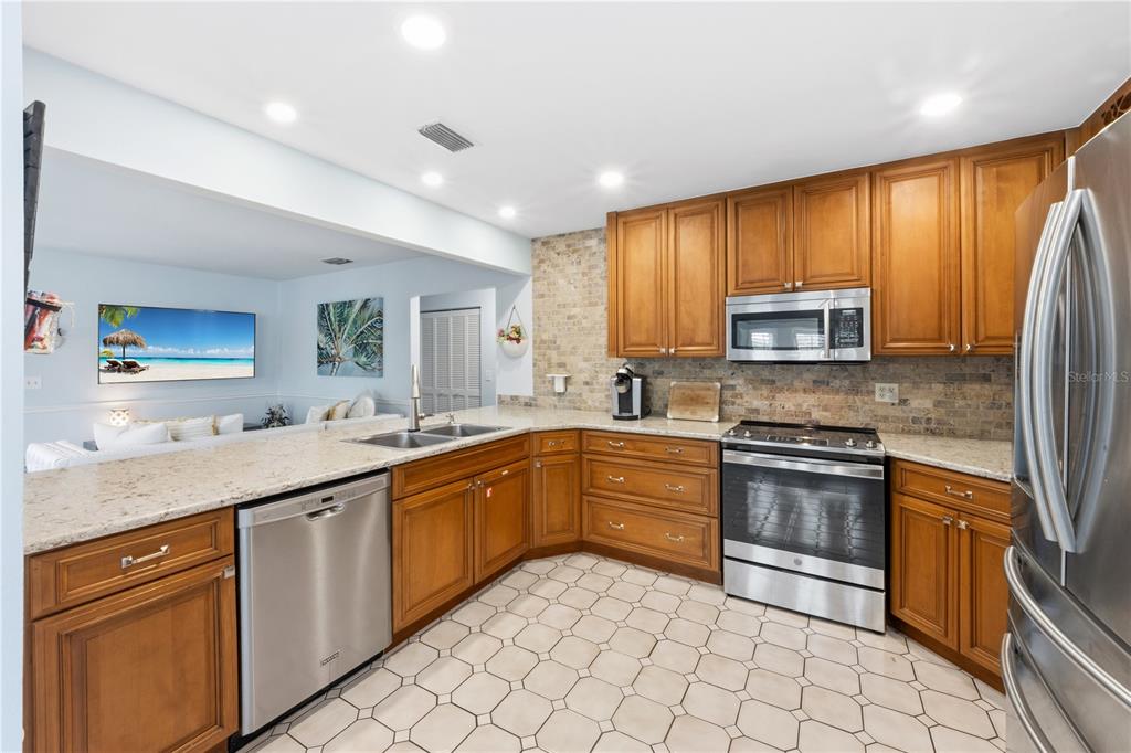 417 Poinsettia Road Anna Maria, FL 34216 - Photo 12 of 34 a kitchen with stainless steel appliances granite countertop a sink and stove top oven with wooden floor
